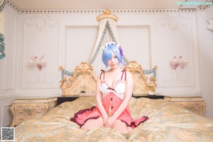 A woman with blue hair sitting on a bed.