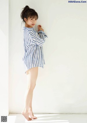 A woman sitting on the floor wearing a blue and white striped shirt.