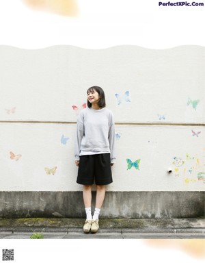 A woman standing in front of a wall with butterflies on it.