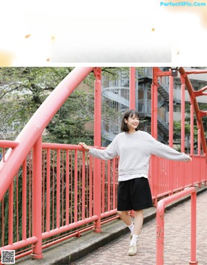 A woman standing next to a red fence talking on a cell phone.