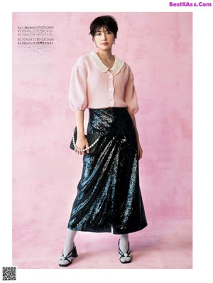 A woman in a green skirt and a black and white jacket.