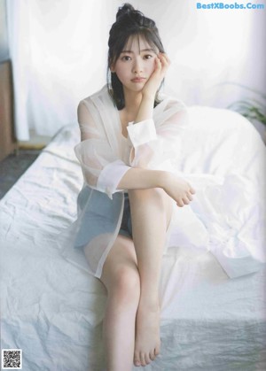 A woman laying on top of a bed next to a pillow.