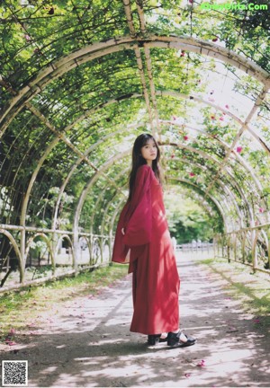 A woman in a red dress walking down a path in the woods.