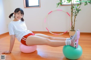 A woman in a white shirt and orange shorts holding a pink stick.