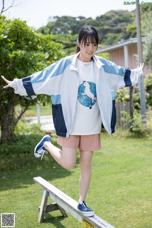 A woman in a blue and white shirt leaning against a fence.