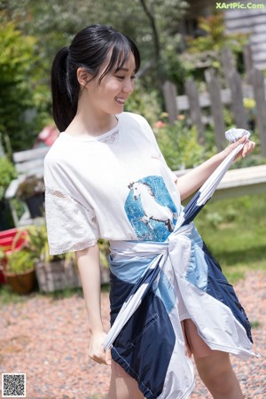 A woman in a blue and white shirt leaning against a fence.