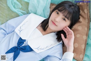 A woman laying on top of a bed next to a pillow.