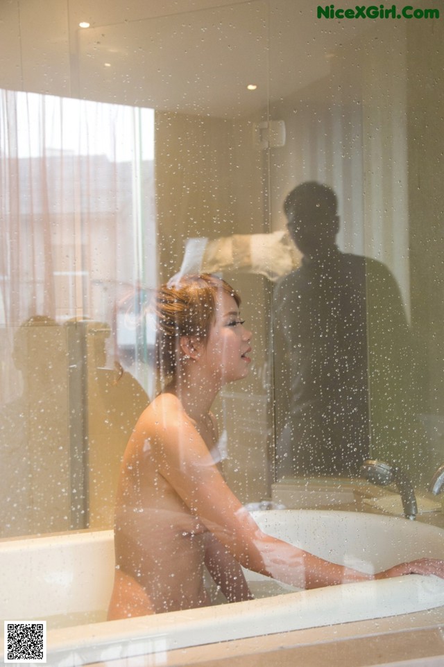 A naked woman taking a bath in a bathtub.