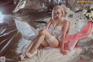 A woman in a white lingerie sitting on a bed.