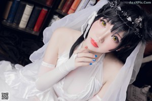 A woman in a wedding dress sitting on a chair.