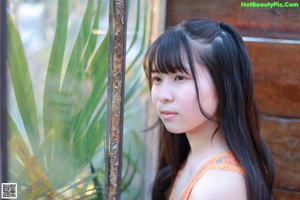A young woman standing in front of a wooden door.