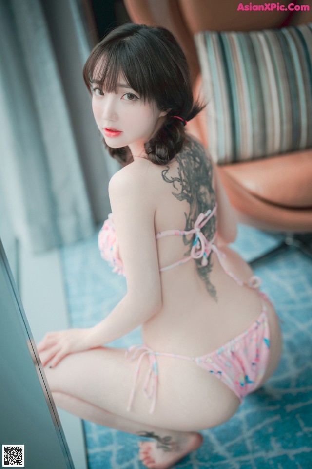 A woman in a pink bikini sitting on the floor.