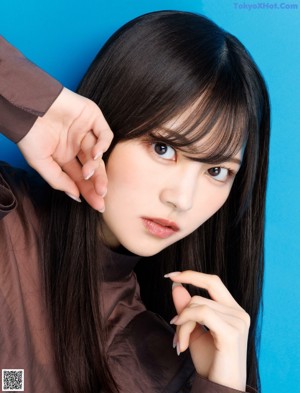 A woman in a brown shirt is posing for a picture.