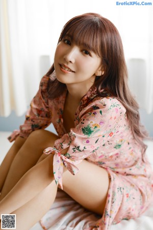A naked asian woman sitting on top of a bed.