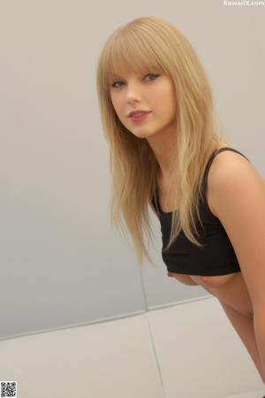 A woman in a black top and gray panties posing on a bed.