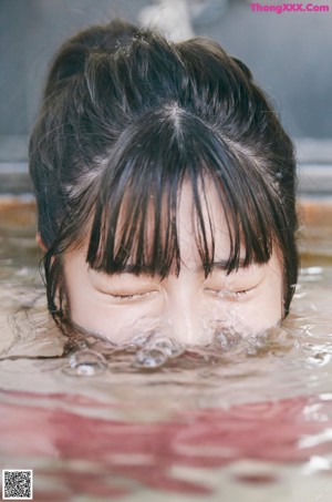 A woman in a pink bikini sitting in a bathtub.