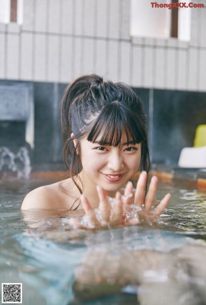 A woman in a pink bikini sitting in a bathtub.