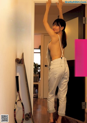 A woman standing in front of a door holding a tennis racket.