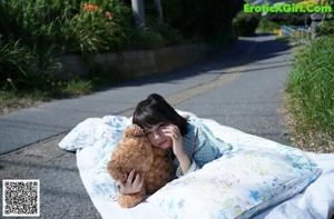 A little girl laying on a blanket with a teddy bear.