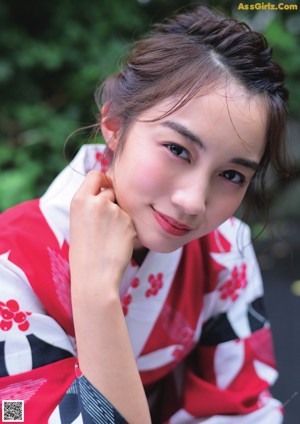 A woman in a red and white kimono sitting on the ground.