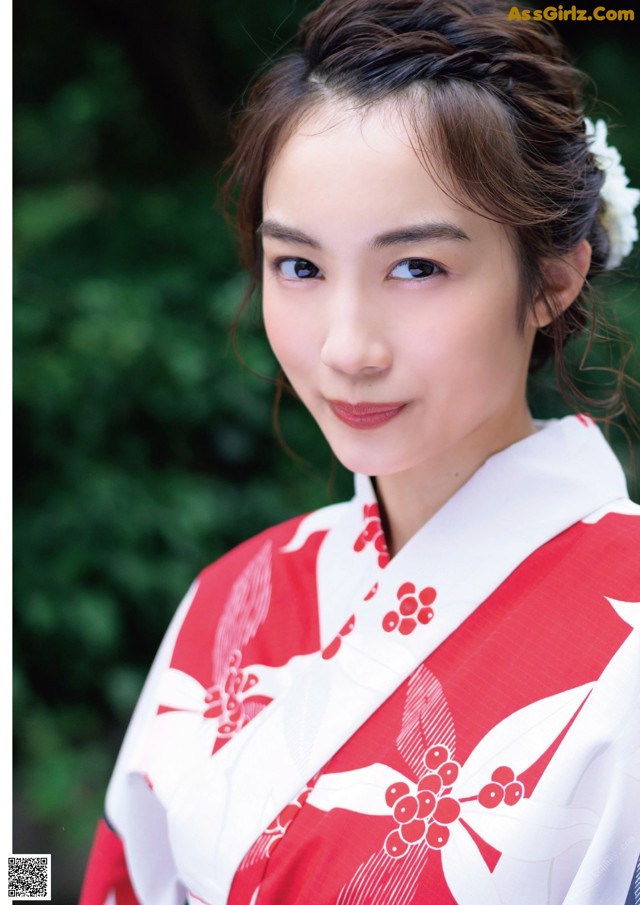 A woman in a red and white kimono posing for a picture.