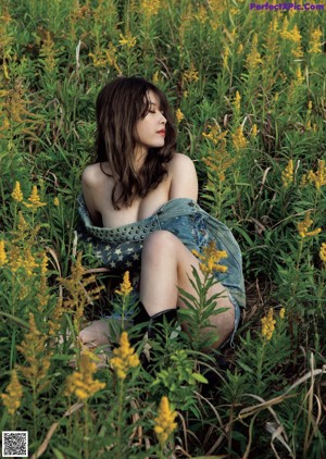 A woman in a black bra top and brown skirt posing for a magazine.