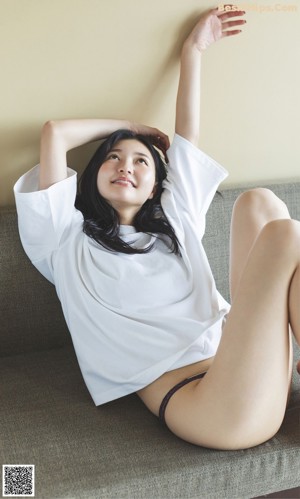 A woman laying on top of a bed covered in white sheets.