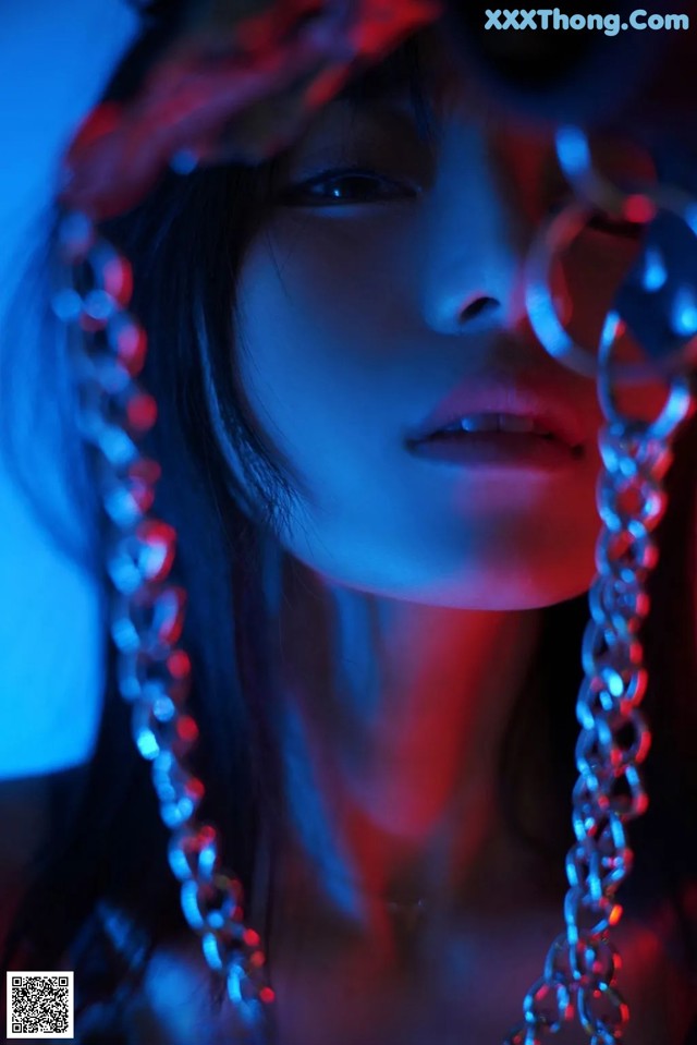 A woman with a chain around her neck in a dark room.