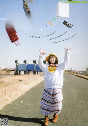 A woman in a white sweatshirt and a yellow hat holding shopping bags.