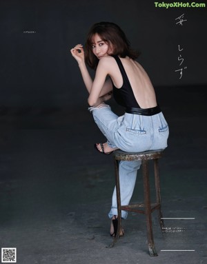 A woman sitting on top of a wooden stool.