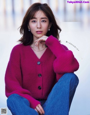A woman sitting on top of a wooden chair on a magazine cover.