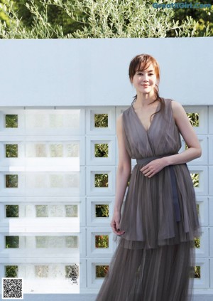 A woman in a black dress standing in a hallway.