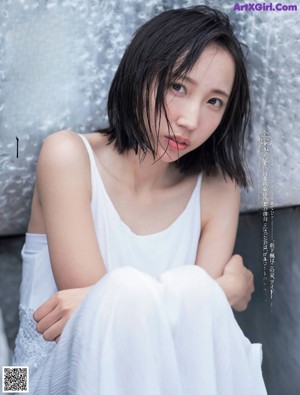 A woman in a white bra top and panties sitting on a bed.