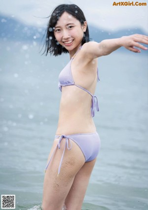 A woman in a purple bikini standing in the water.