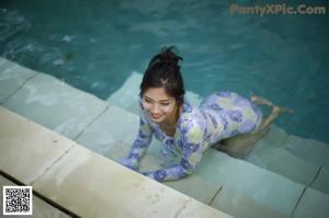 A woman in a white bathing suit standing next to a hot tub.