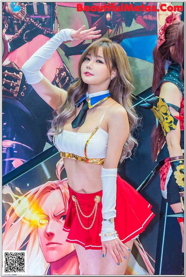 A woman in a white top and red skirt posing for a picture.