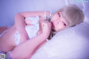 A woman in a white lingerie sitting on a bed.