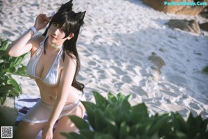 A woman in a white bikini laying on a beach.