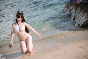 A woman in a white bikini standing on a beach.