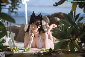 A woman in a white bikini laying on a rock.