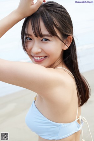 A woman in a blue and white dress standing on a beach.