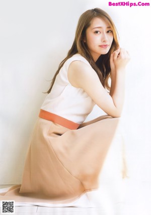 A woman in a yellow top and floral skirt talking on a phone.