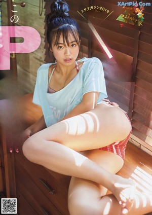A woman sitting on top of a wooden dresser.